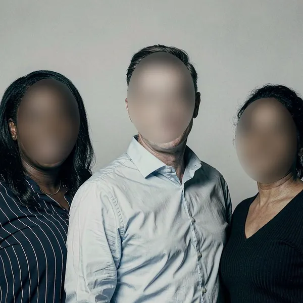 Blur face online result: the same group photo with all three faces blurred and anonymized in one pass, while hair, clothing and background stay sharp